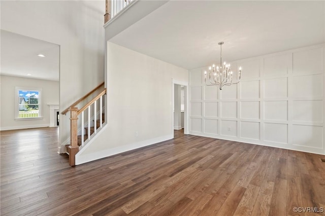 unfurnished dining area with baseboards, wood finished floors, stairs, and a decorative wall