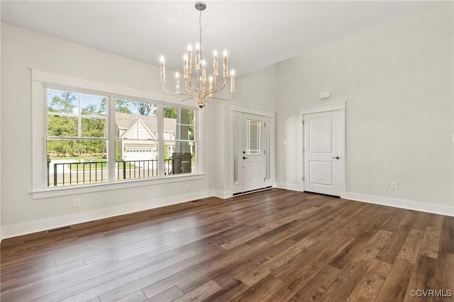 unfurnished dining area featuring dark wood finished floors, a notable chandelier, visible vents, and baseboards