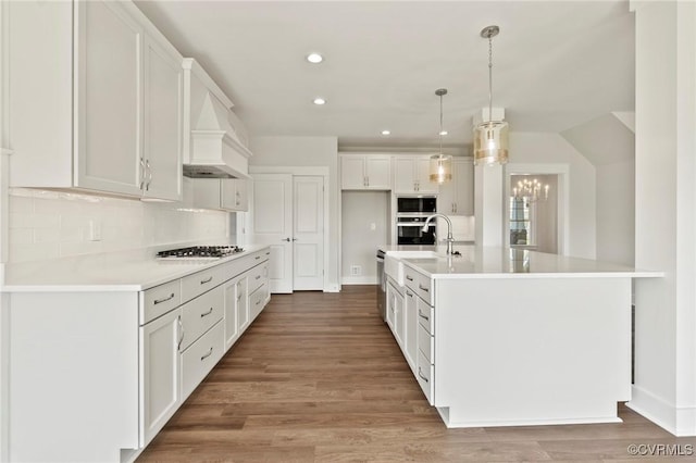 kitchen featuring stainless steel appliances, white cabinetry, backsplash, and light wood finished floors