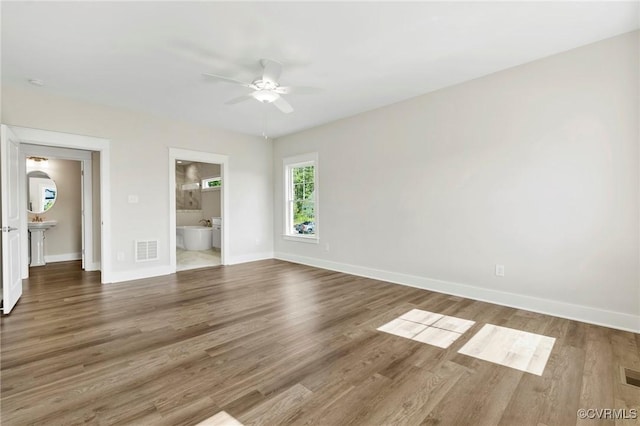 spare room with a ceiling fan, wood finished floors, visible vents, and baseboards