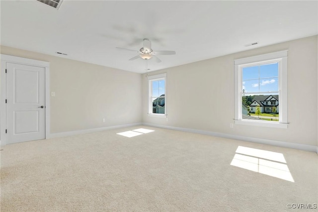 carpeted spare room with plenty of natural light, visible vents, baseboards, and ceiling fan