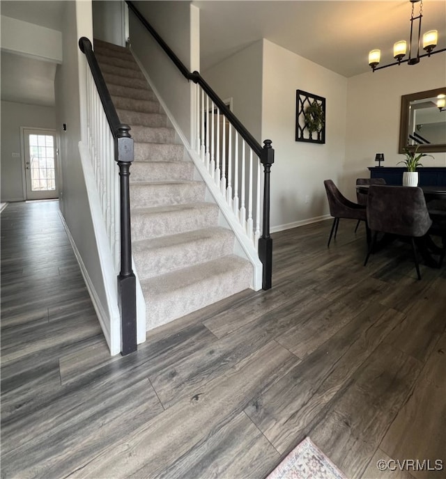 stairway featuring an inviting chandelier, baseboards, and wood finished floors