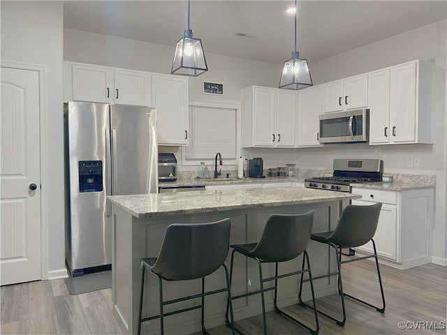 kitchen with a sink, a kitchen island, white cabinetry, and stainless steel appliances