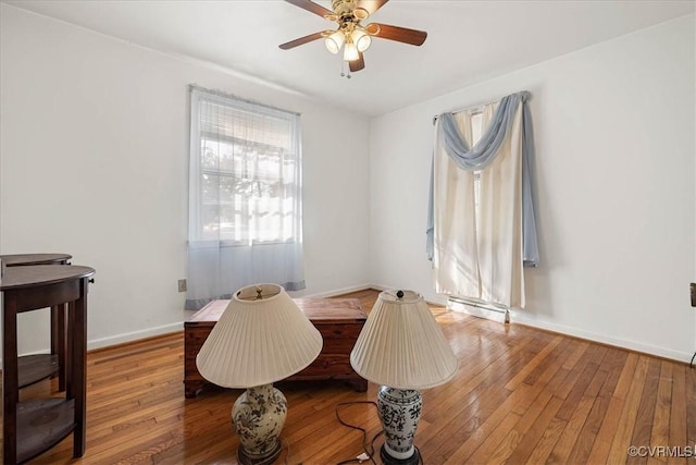 dining area featuring baseboards, wood-type flooring, and a ceiling fan