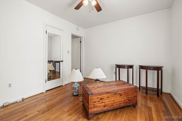 sitting room featuring baseboards, light wood-type flooring, and ceiling fan