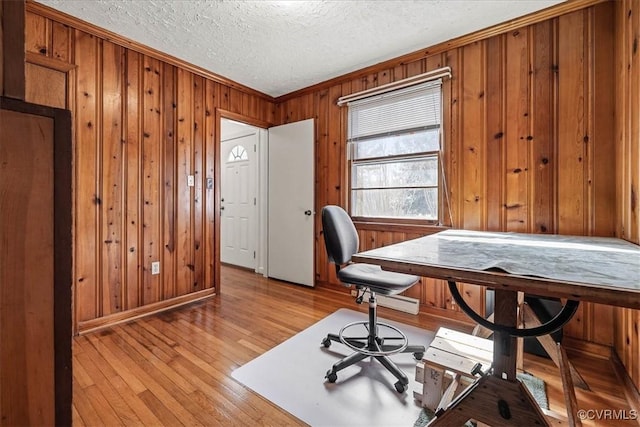 home office with a textured ceiling, wood walls, crown molding, light wood finished floors, and baseboards