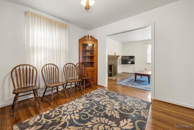 sitting room featuring baseboards, a brick fireplace, and hardwood / wood-style floors