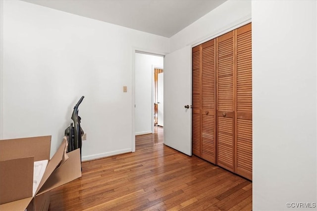 unfurnished bedroom featuring a closet, baseboards, and light wood-style floors