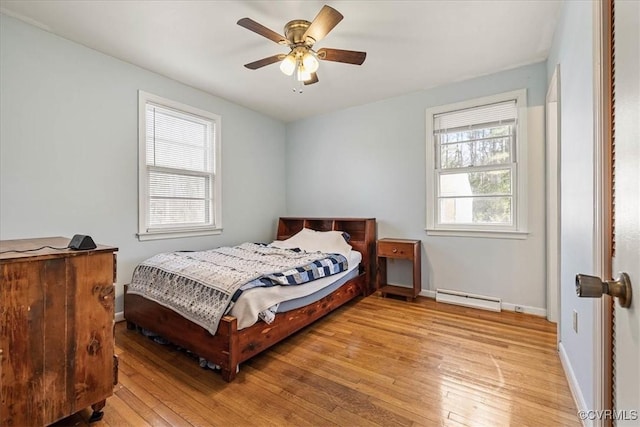 bedroom featuring baseboard heating, ceiling fan, baseboards, and light wood-style floors