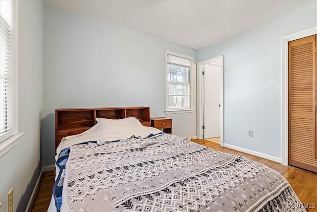 bedroom with a closet, baseboards, and wood finished floors