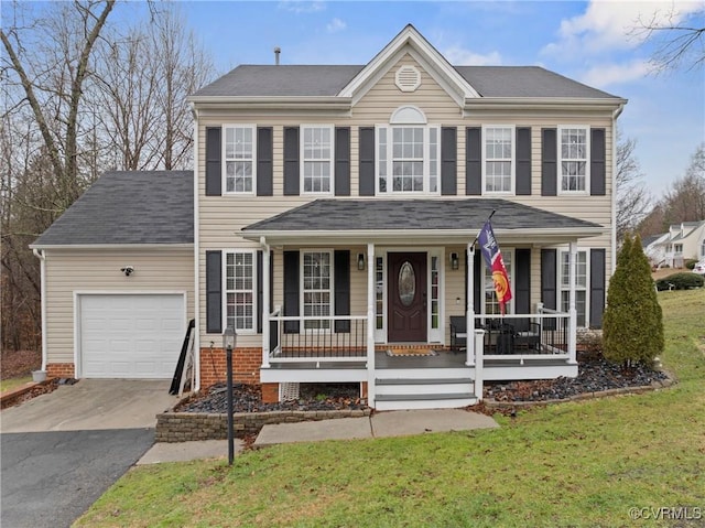 colonial-style house featuring a porch, a garage, a front yard, and aphalt driveway