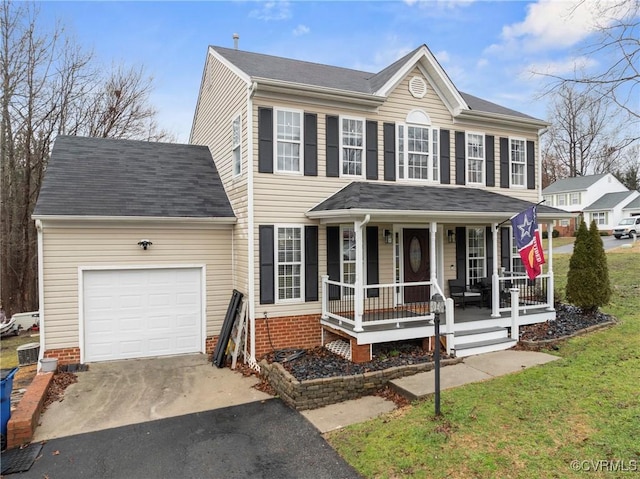 colonial home featuring aphalt driveway, a porch, a front yard, a shingled roof, and a garage