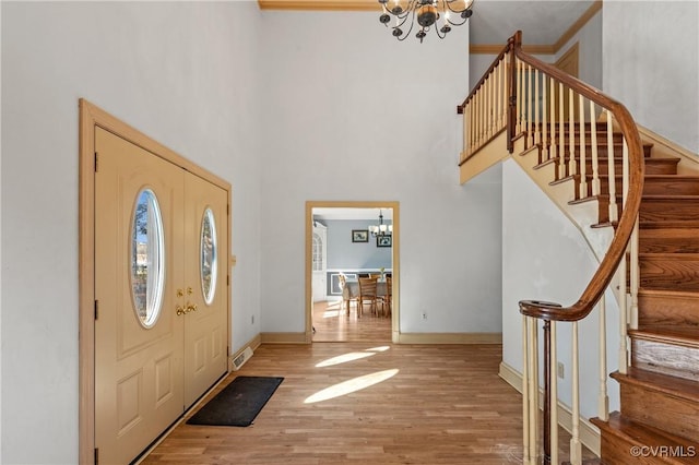 foyer featuring a notable chandelier, wood finished floors, baseboards, and a towering ceiling