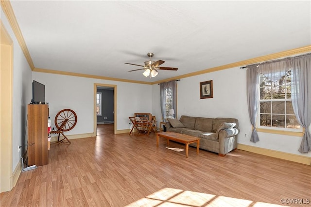 living area featuring light wood-type flooring, baseboards, ornamental molding, and a ceiling fan