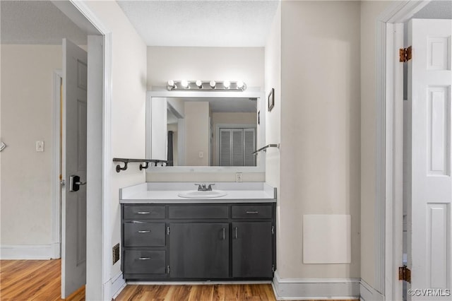 bathroom with vanity, wood finished floors, and baseboards