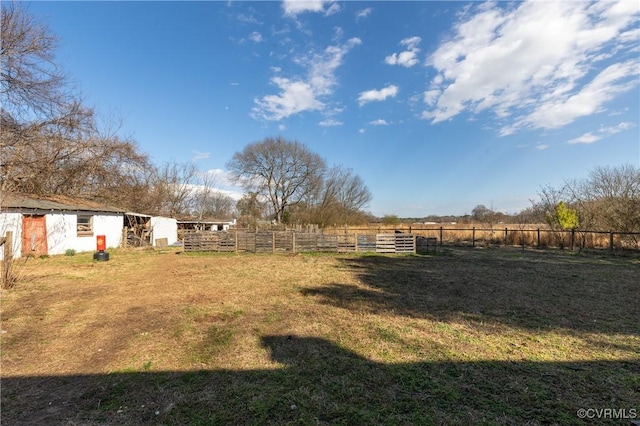 view of yard featuring a rural view, an outbuilding, and fence