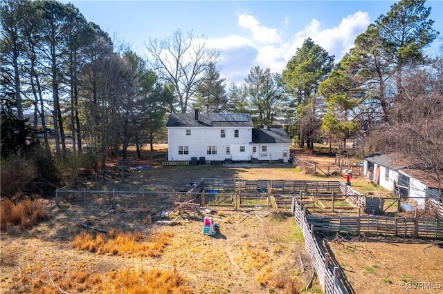 rear view of house featuring solar panels and fence