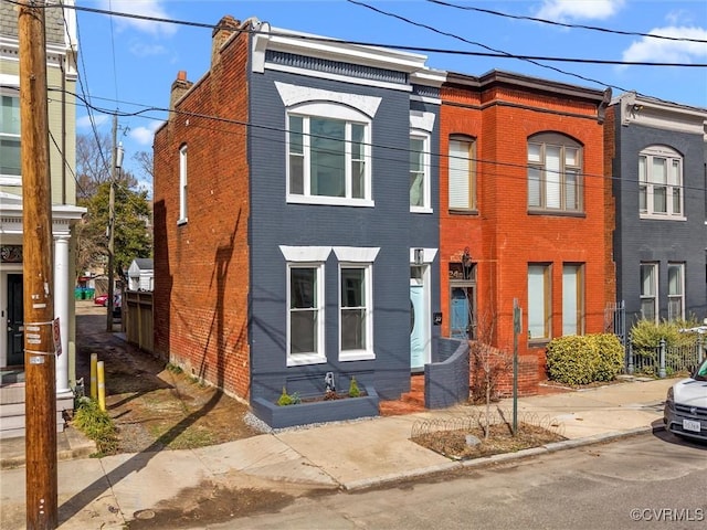 townhome / multi-family property featuring brick siding and a chimney