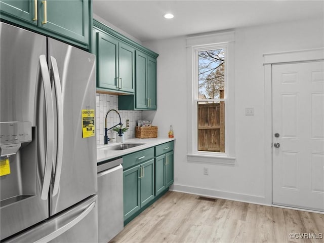 kitchen with green cabinets, tasteful backsplash, appliances with stainless steel finishes, and a sink