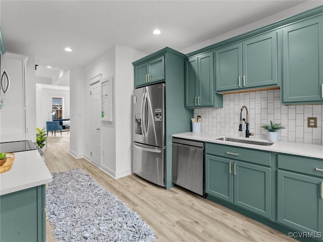 kitchen featuring a sink, stainless steel appliances, green cabinets, and decorative backsplash