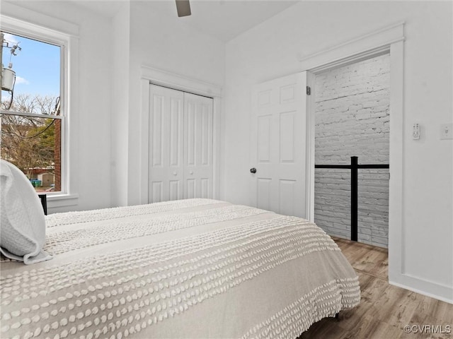 bedroom with a closet, baseboards, wood finished floors, and a ceiling fan