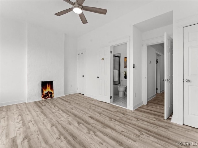 unfurnished living room with baseboards, a ceiling fan, wood finished floors, and a fireplace