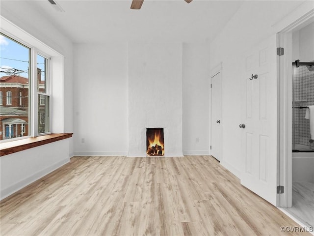 unfurnished living room with visible vents, wood finished floors, a fireplace, baseboards, and ceiling fan