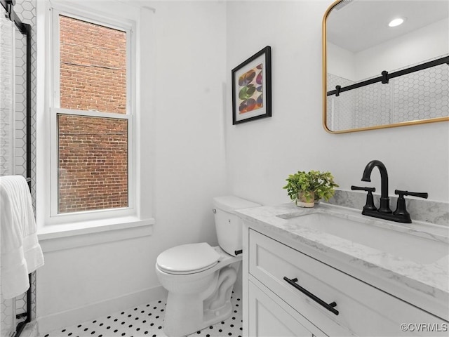 bathroom featuring toilet, vanity, plenty of natural light, and a shower