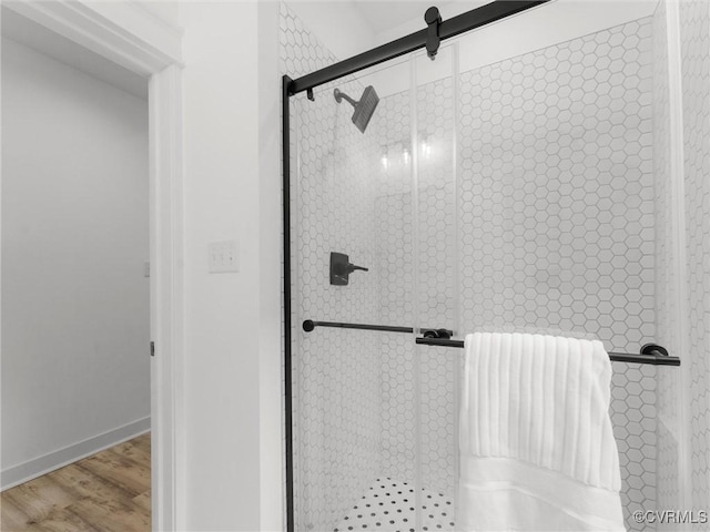 full bathroom featuring baseboards, wood finished floors, and a stall shower