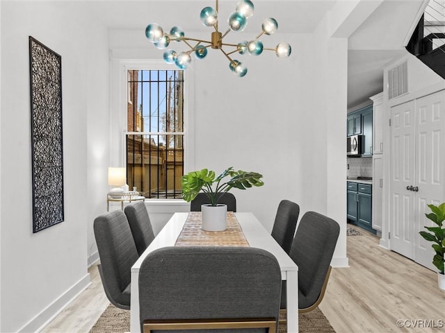 dining area with a chandelier, visible vents, light wood-type flooring, and baseboards