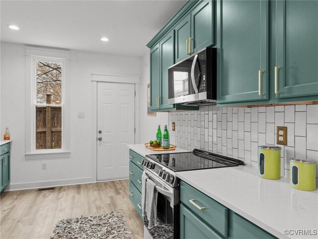 kitchen with green cabinets, light countertops, light wood-style floors, and appliances with stainless steel finishes