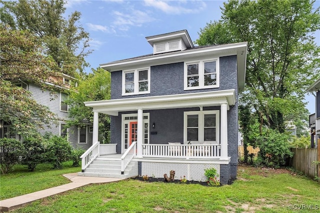 traditional style home with a porch, fence, a front lawn, and stucco siding