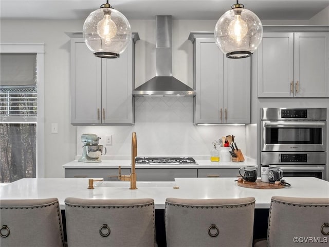 kitchen featuring stainless steel appliances, tasteful backsplash, wall chimney exhaust hood, and light countertops