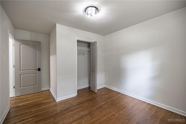 unfurnished bedroom featuring a closet, baseboards, and dark wood-style flooring