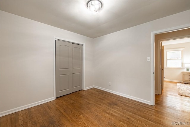 unfurnished bedroom with a closet, baseboards, and wood finished floors