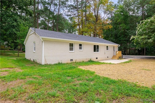 back of house with crawl space, a yard, brick siding, and roof with shingles