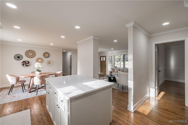 kitchen featuring dark wood-style floors, light stone countertops, white cabinets, crown molding, and a center island