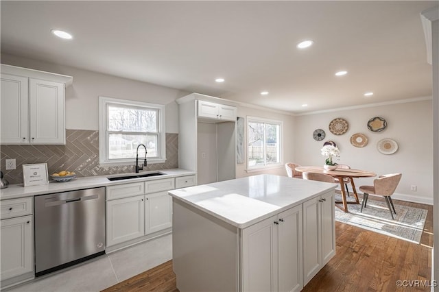 kitchen with light wood-type flooring, a sink, tasteful backsplash, white cabinets, and dishwasher