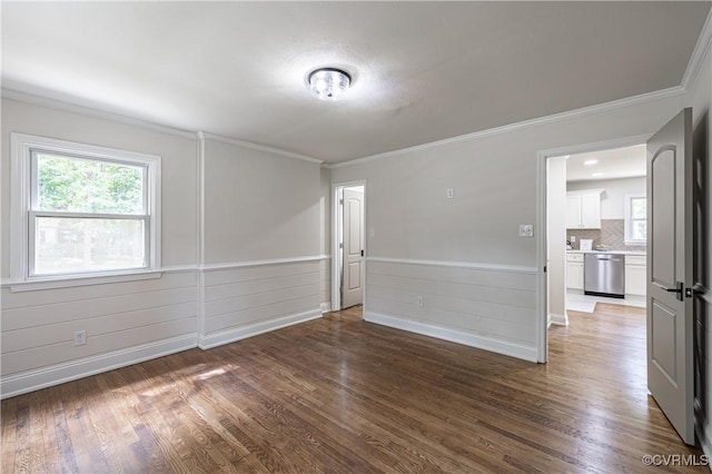 spare room with plenty of natural light, wood finished floors, wainscoting, and ornamental molding