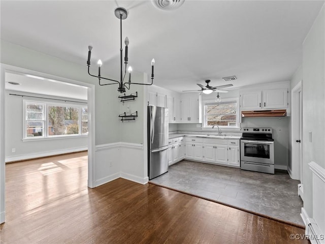 kitchen featuring dark wood finished floors, a sink, stainless steel appliances, light countertops, and under cabinet range hood