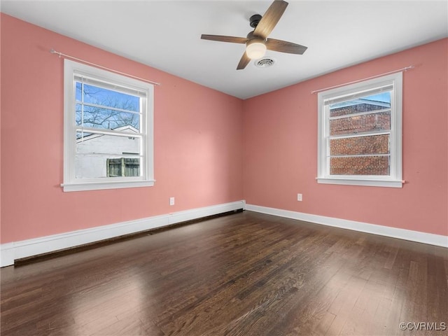 unfurnished room featuring visible vents, a ceiling fan, dark wood finished floors, a baseboard radiator, and baseboards