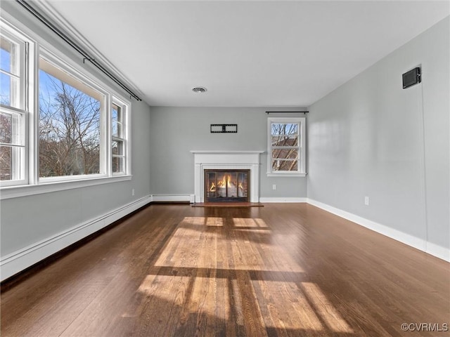 unfurnished living room with wood finished floors, visible vents, baseboards, a fireplace with flush hearth, and baseboard heating