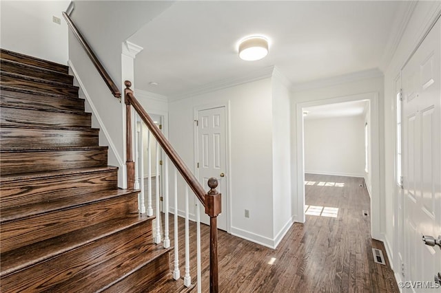 stairway with crown molding, wood finished floors, visible vents, and baseboards