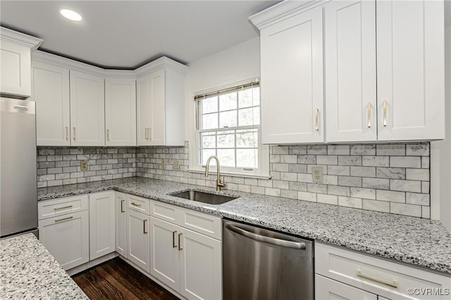 kitchen featuring a sink, appliances with stainless steel finishes, white cabinets, decorative backsplash, and dark wood-style flooring