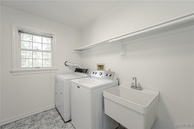 clothes washing area with laundry area, washer and clothes dryer, baseboards, and a sink