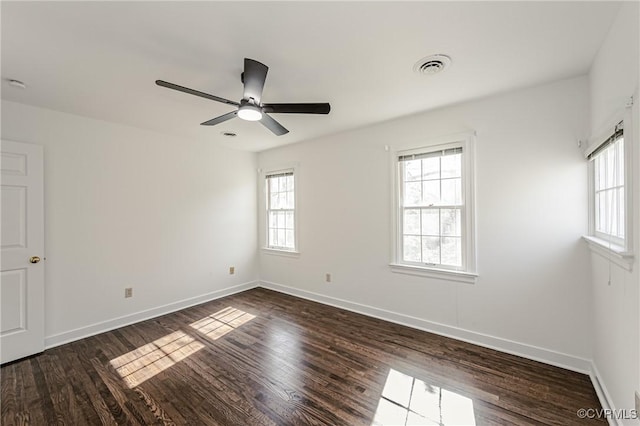 spare room featuring visible vents, baseboards, ceiling fan, and dark wood-style flooring