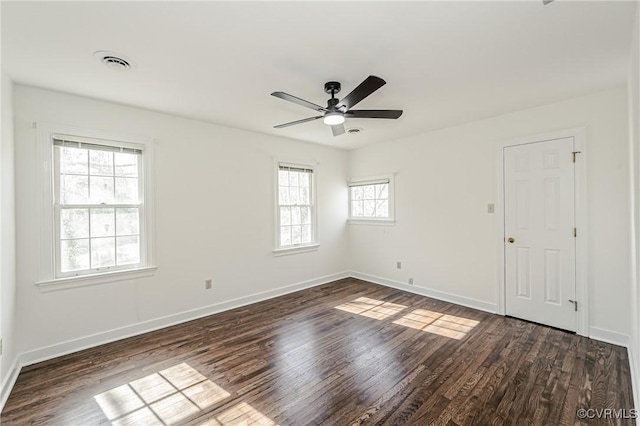 unfurnished room featuring visible vents, baseboards, dark wood-style floors, and a ceiling fan