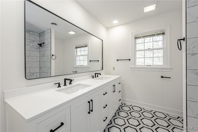 full bath featuring double vanity, a healthy amount of sunlight, baseboards, and a sink