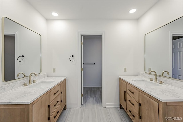 full bath featuring two vanities, baseboards, and a sink