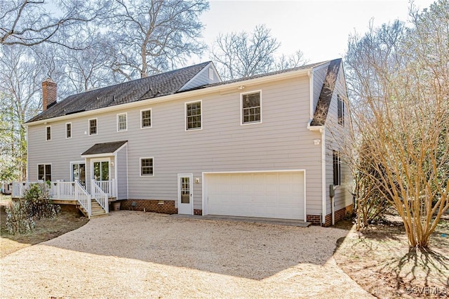 view of front of home with crawl space, an attached garage, a chimney, and driveway